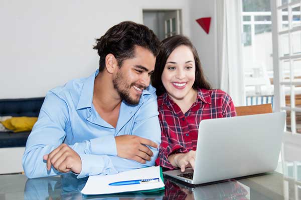 Cozy couple sitting at table looking at laptop