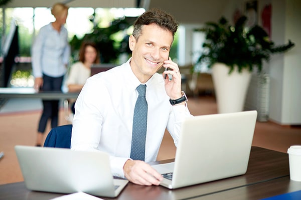 A businessman on the phone in front of a laptop at a desk