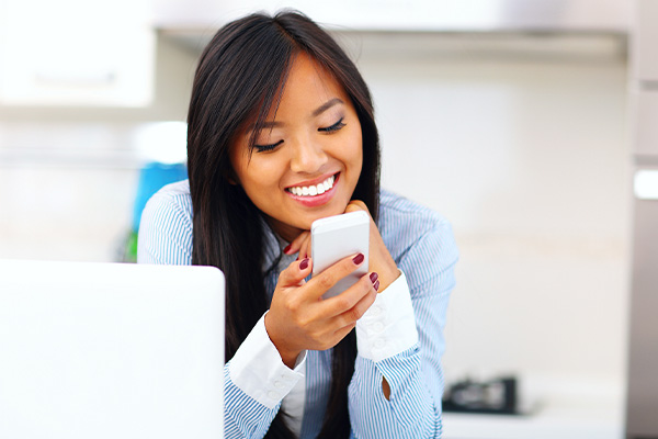 A woman holding a coffee cup and a cellphone